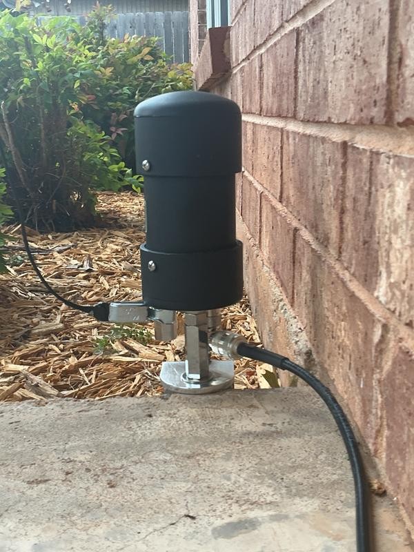 Boîtier HOA Buster noir au pied d'une descente de gouttière, coaxial branché